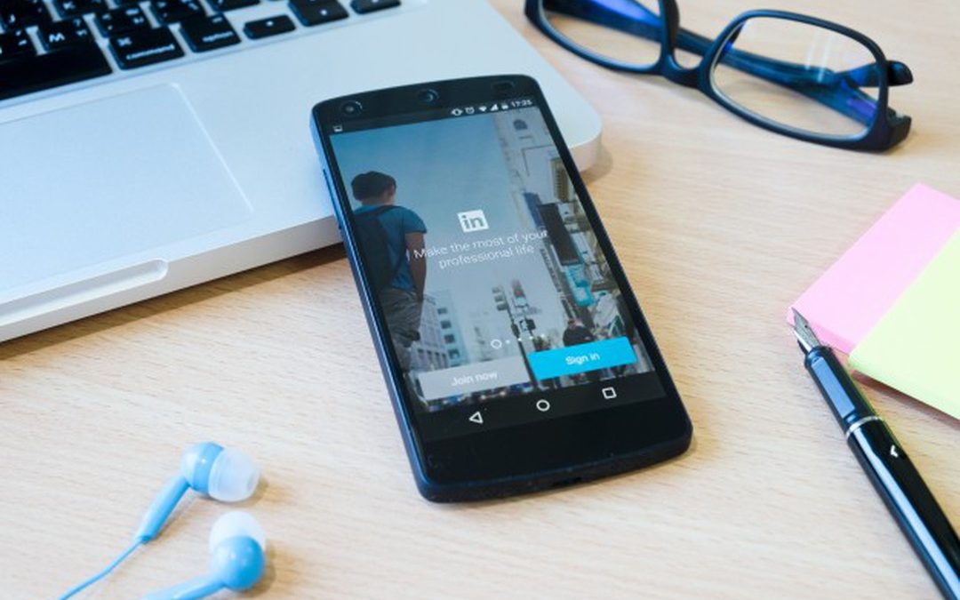 Celular sobre a mesa, com a tela ligada na página de login do LinkedIn.